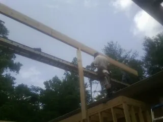 Carpenter setting a ridge beam over a new addition frame — Ice Dam Removal by Roofing Brothers in Griffith