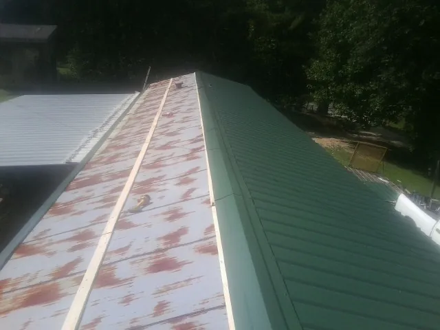 Old rusted panels beside newly installed green metal roofing — Wind Damage Roof Repair by Roofing Brothers in Griffith