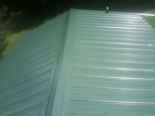 New green metal panels meeting at the ridge of a roof — Flat Roof Repair work by our crew in Griffith