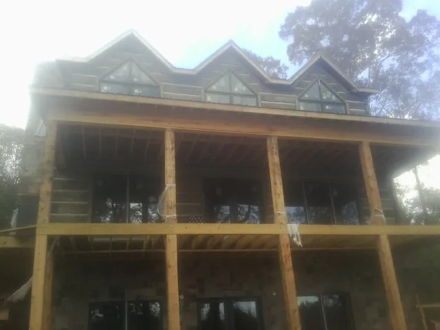 Dormers and porch framing on a large log home under construction — Roof Coating work by our crew in Griffith