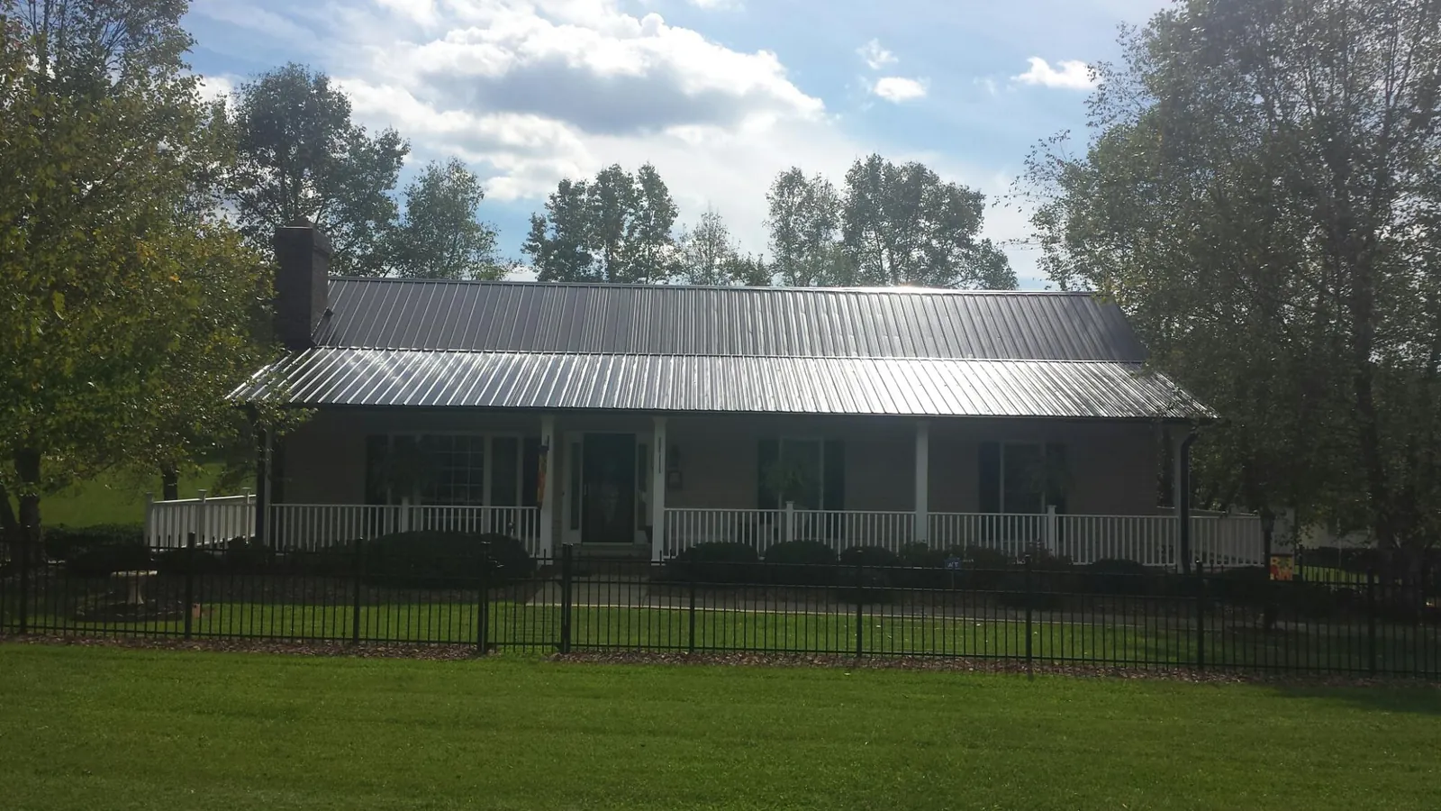 Gray metal roof on a brick ranch with a full width front porch — Gutter Guard Installation work by our crew in Griffith